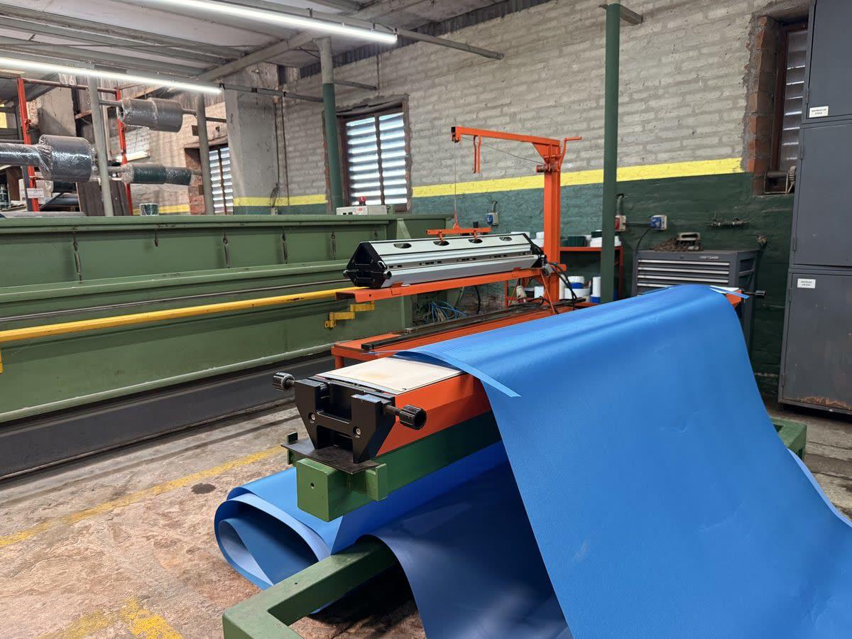 Máquina cortadora procesando banda PVC azul grado alimenticio — Warbel S.A.