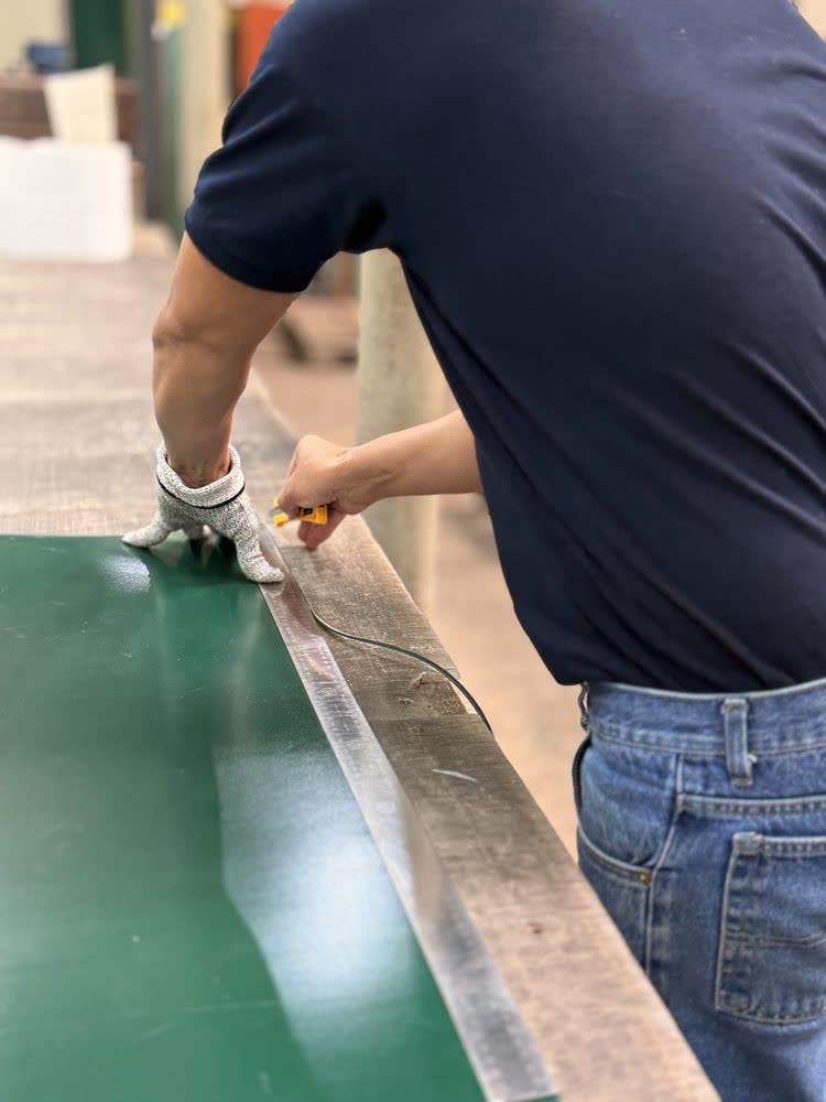 Técnico realizando corte de precisión en banda transportadora verde — mantenimiento Warbel